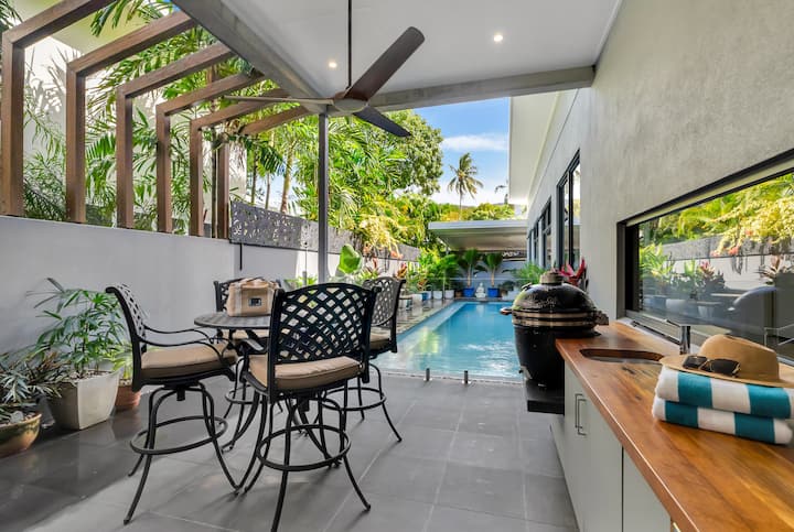 Covered poolside alfresco area with an outdoor dining setting, looking along the pool.