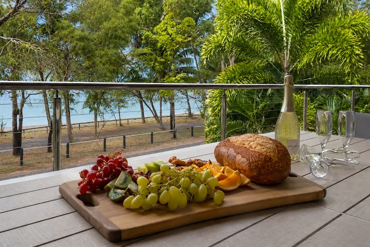A grazing board on the balcony table, looking down across the quiet road and foreshore trees to the sea.
