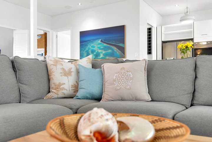Lounge sofa beneath a large aerial reef photograph, "Reef River" by Brooke Miles.