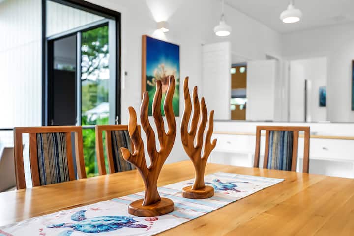Carved timber coral sculptures on the dining table, with reef photography beyond.