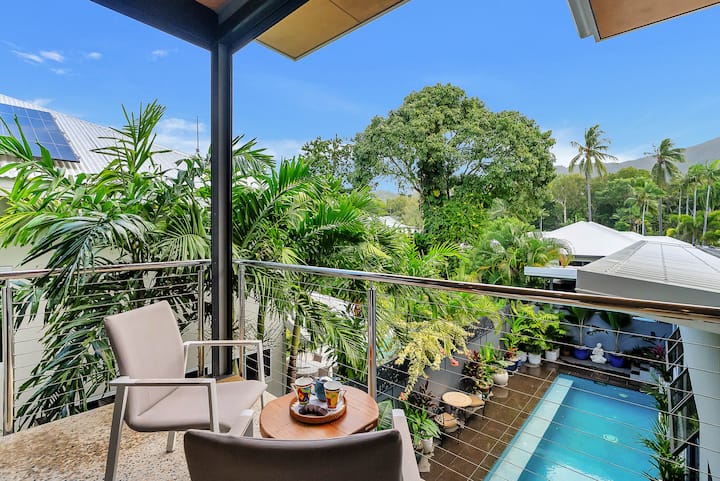 Western balcony with chairs, overlooking the pool and palms towards the hills.