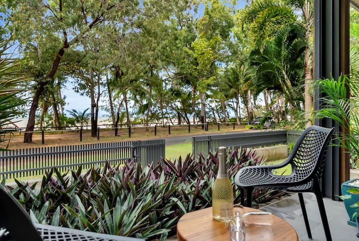 Private patio outside the master bedroom with chairs and a small table, looking through the trees towards the sea.