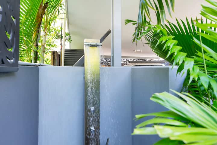 Outdoor shower behind a screen beside the pool.
