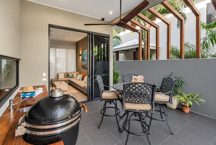Covered poolside alfresco dining area with outdoor table and chairs.